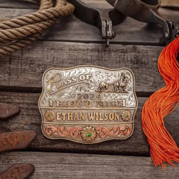 A custom class belt buckle for Frisco High School with personalized name featuring a golden bronze team roping figure 